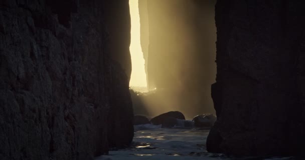 在英国康沃尔的Nanjizal 阳光透过Zawn Pyg Rock Archves 在落日余晖下拍击海浪 — 图库视频影像