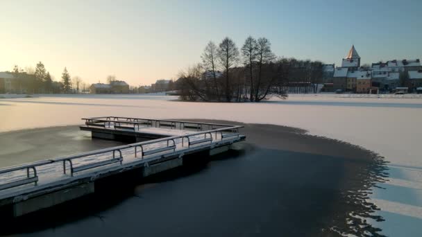 ポーランドのGorowo Ilaweckieのコミュニティで日の出の陶器の池で凍結した雪の橋 — ストック動画