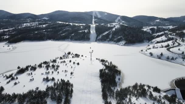 セルビアのズラティボールだ ホワイトウィンターランドスケープの凍った湖の上のゴンドラルートとキャビンの空中ビュー ドローンショット — ストック動画