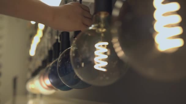 一个人在一排排灯泡上一个接一个地在一个灯柜里开灯 一排排灯笼里发光的灯泡灯 — 图库视频影像