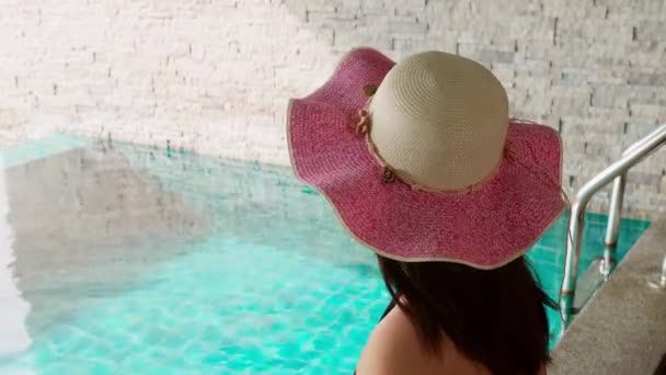 Vista Trasera Una Mujer Irreconocible Sentada Borde Piscina Con Sombrero — Vídeos de Stock