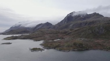 Hava aracı Norveç 'in Lofoten şehrinde bulutlu, kayalık kıyılara ve dağlara bakıyor.