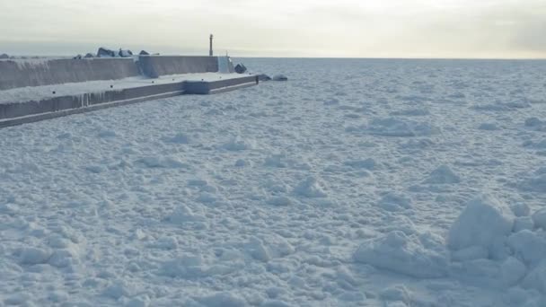 凍る流氷に沿った空中防波堤横の沢木港 スロードリー フォワード — ストック動画