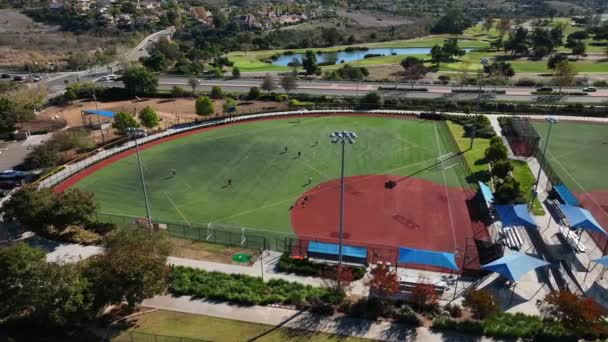 加州卡尔斯巴德Alga Norte公园一个棒球场的旋转无人机射击 男孩子们在球场上踢足球 — 图库视频影像