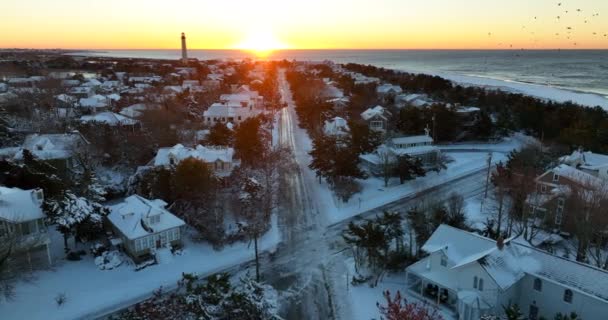 美丽的海滨别墅在日出时分 灯塔在冬雪中 街上雪覆盖着未耕作的房屋 — 图库视频影像