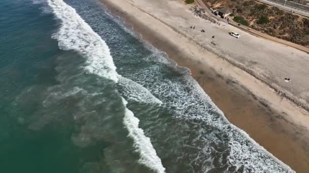 海岸線に沿って砂浜に衝突する波のビデオと 米国カリフォルニア州カールスバッドの美しい町を傾ける — ストック動画