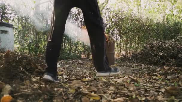 汚れた服を着た男が調整し フォークで庭の煙緑色のゴミ捨て場の火を吸う スローモーションロックされたショット — ストック動画