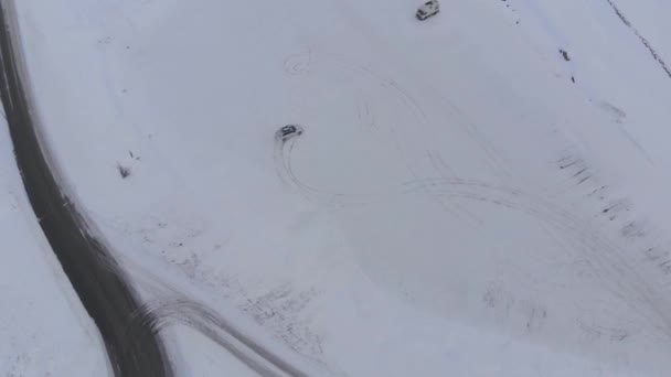 雪上駐車場 暗い曇りの日に漂流車を見下ろす空中ドローンビュー — ストック動画