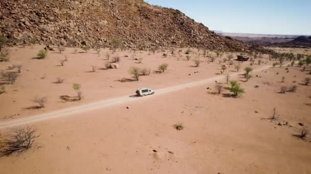 空中パンは許しのない砂漠の風景を探索するオフロード車を明らかにする — ストック動画