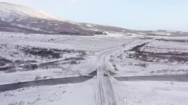 在靠近河流和白雪的冬季路上驾驶的汽车的空中覆盖着森林 无人驾驶飞机射击 — 图库视频影像