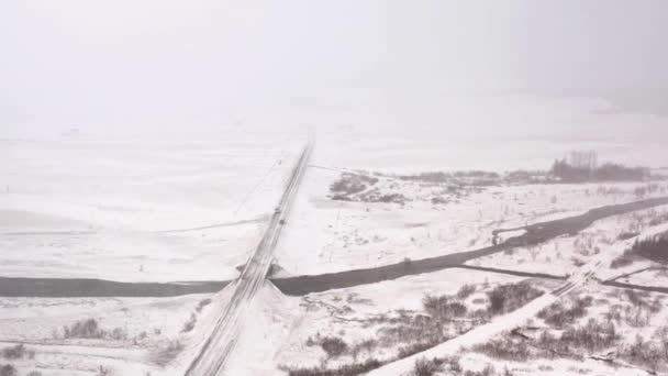 在降雪中沿着冬季雪地公路行驶的车辆 空中无人驾驶飞机射击 — 图库视频影像