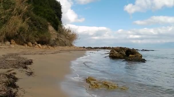 曇りの日に砂の海のビーチで海の水から出てくる岩の行でビーチを歩いている間に撮影されたハメ撮り — ストック動画
