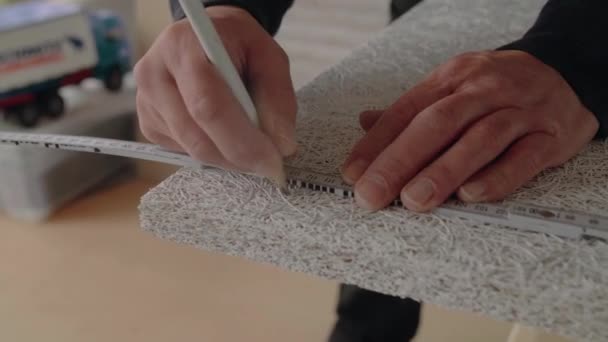 鉛筆と折り畳み式の定規を使って音響パネルをマーキングするハンディマンの手の詳細 — ストック動画