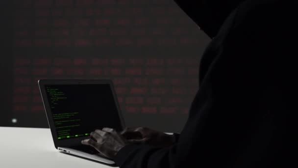 Muž hacker v mikině pomocí notebooku pomocí počítačových serverů. internetová bezpečnost, počítačová trestná činnost, informační technologie, zpracování dat a počítačové servery. Bez tváře.