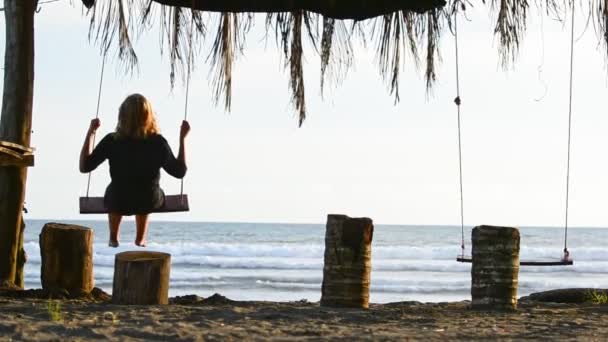 Young Woman Sitting Oceanfront Swing Set Swaying Back Forth While — Stock Video