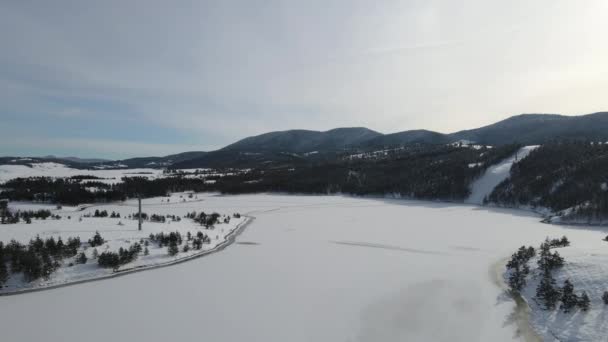 セルビアのZlatibor山の冬の風景の空中ビュー 冷凍雪の湖と丘 ドローンショットキャップ — ストック動画