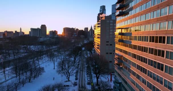 市区公寓楼在冬季大雪中 晨曦映照城市景观 — 图库视频影像