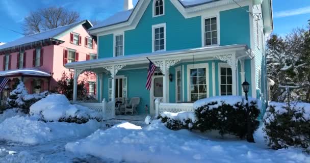 新鮮な冬の雪の中でアメリカのビクトリア朝の家 空中台座の上昇ショットを確立する 玄関前のアメリカ国旗 — ストック動画