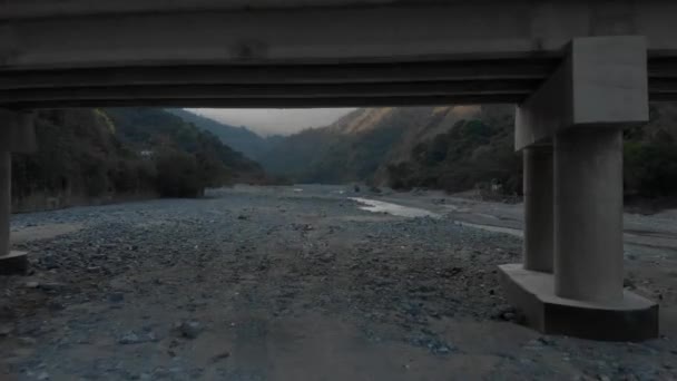 フィリピン ベンゲットの山間部の乾燥河床にまたがるセメント橋の空中アプローチ — ストック動画