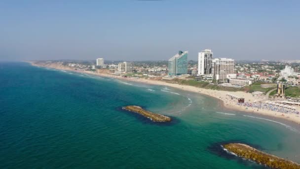 澄んだ青と緑の色の地中海の水が防波堤と晴れた日にイスラエルのヘルズリヤの高い観光ビーチで転がります — ストック動画