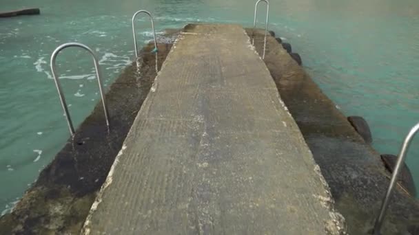 五三島のぬれた滑りやすい石の桟橋を歩くときに内陸の海の洞窟を明らかにする — ストック動画