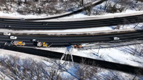 豪雪後の高速道路の空中ビュー 作業車両は高速道路から雪をクリアするために出口を閉鎖した 無人機のカメラは下に傾けられ 車が運転する際に作業車両の上をホバーします — ストック動画