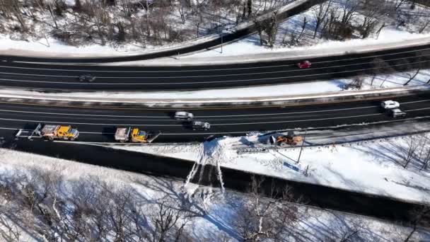 雪嵐の後の高速道路の空中ビュー 作業車両は高速道路から雪をクリアしている 無人機のカメラは左側の作業車両の上に傾いて右側にパン車が運転するように — ストック動画