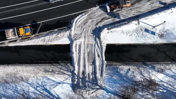 大雪过后高速公路的鸟瞰图 维修车辆关闭一个出口 以清除高速公路上的积雪 无人驾驶相机倾斜下来 在几辆车开过的时候在上面盘旋 — 图库视频影像