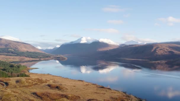 雪に覆われた山々 森と美しいまだ反射水を持つスコットランドのハイランドでグレン エティブとロッホ エティブの壮大な冬の景色を明らかにするためにゆっくりと反転空中ドローン映像 — ストック動画