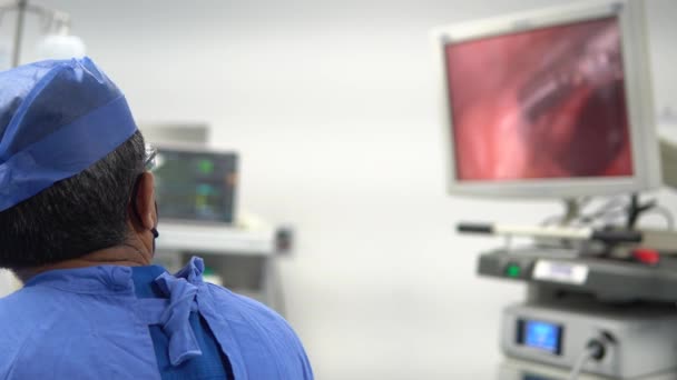 一位穿着蓝色灭菌服的医生在腹腔镜手术中对监视器的观察 — 图库视频影像