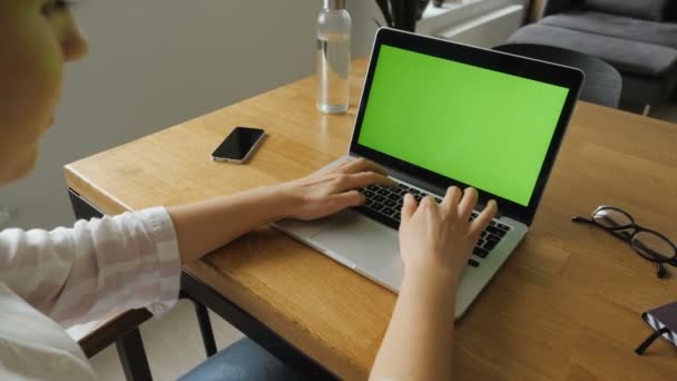 家庭やオフィス環境の木製のテーブルの上にラップトップコンピュータで作業している若い女性を見ることができます — ストック動画