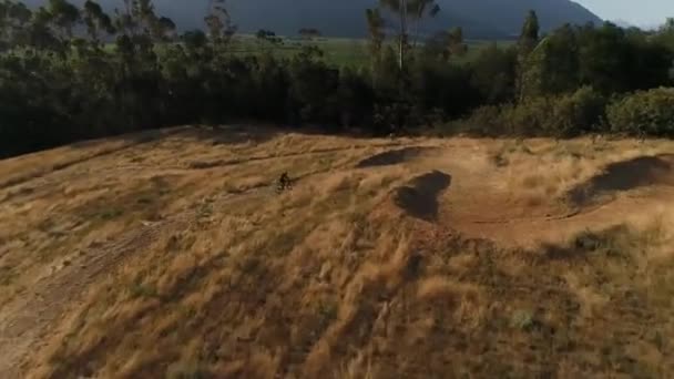 Aerial Drone Shot Segue Motociclista Ciclismo Caminho Terra Seguida Zooms — Vídeo de Stock