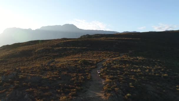 Flygfoto Manlig Joggare Grusväg Genom Ett Berg Vid Solnedgången — Stockvideo