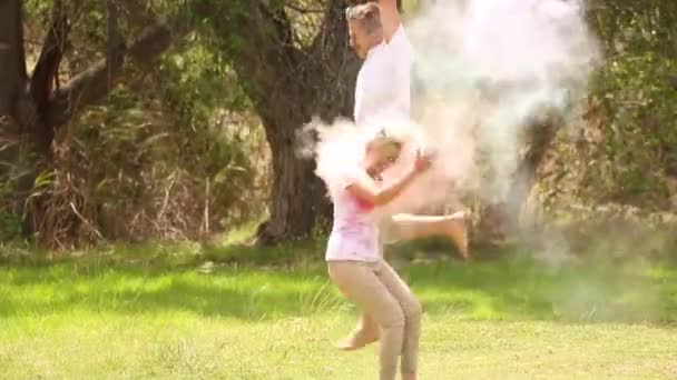 若いカップルは 美しい晴れた日に公園で互いに飛び上がる粉塗料で遊んでいます — ストック動画