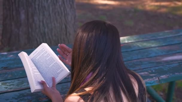 Mahasiswa Membaca Buku Sambil Duduk Bangku Taman Dikelilingi Oleh Alam — Stok Video