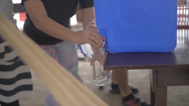若い女性はプラスチック容器からガラスに水を注ぐ — ストック動画
