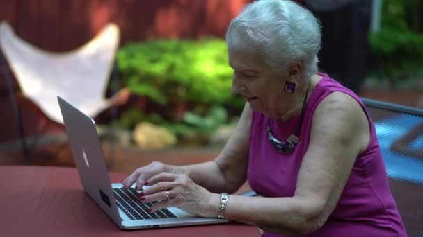 Ηλικιωμένη Γυναίκα Χαμογελά Καθώς Πληκτρολογεί Στο Πληκτρολόγιο Του Φορητού Υπολογιστή — Αρχείο Βίντεο