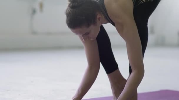 在一个白色的仓库工作室里 一个柔韧的年轻黑发女子练习瑜伽的特写镜头 — 图库视频影像
