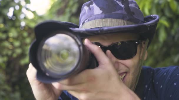 若い千年の写真家は彼の目にカメラを持ち上げ 笑顔と笑いスローモーション — ストック動画