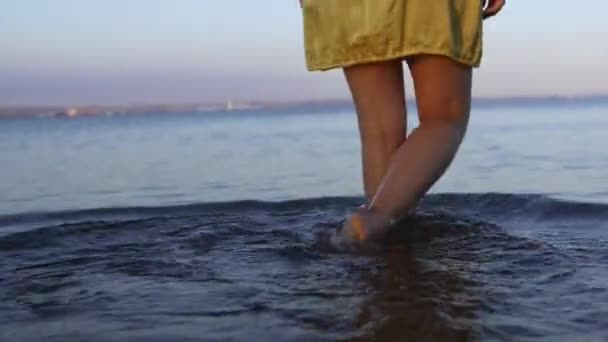 日落时分 一个穿着黄色缎子裙在海里划桨的年轻女子手持中镜头 水的波纹和反射 — 图库视频影像
