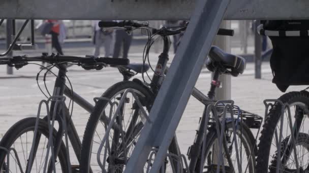 自行车被锁在火车站外的自行车架上 旁边的公共汽车站后面有通勤者 — 图库视频影像