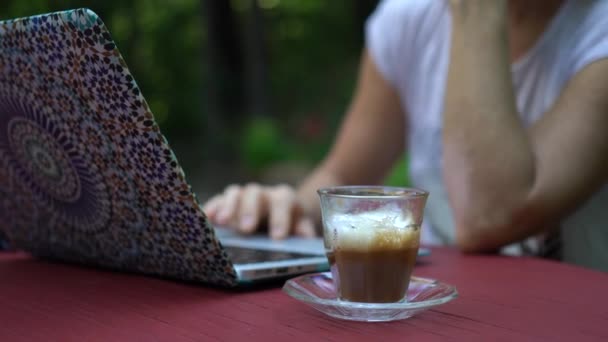 在室外庭院里 与在笔记本电脑上工作的注意力不集中的女人一起喝咖啡 — 图库视频影像