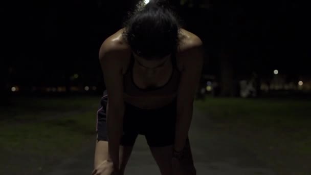 若いフィット感と汗びっしょりの地中海の女性の移動ショットは 夜に公園で実行してから彼女の息をキャッチします 準備が整ったら — ストック動画