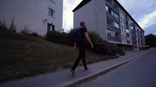 夏の終わりの夜の間 スウェーデンのストックホルム郊外を歩く白人男性 彼は歩くと モデルに続く安定したグライドカム映像 — ストック動画