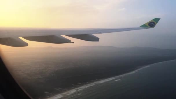 Снимок Самолёта Летящего Континенту Рассвете Бразильским Флагом Правом Крыле — стоковое видео