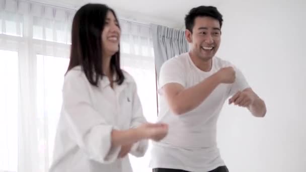 Happy Asian couple dancing together at home.