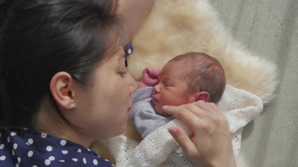 Newborn baby face to face with mother on sheepskin rug. Mother touches babies cheek.