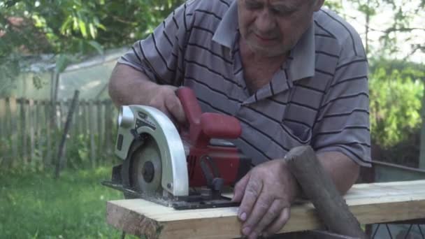 Anciano Con Camisa Rayas Cortando Una Tabla Madera Con Una — Vídeo de stock