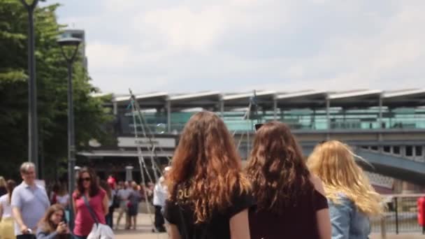 Trio mladých dívek sledujících pouličního umělce, jak dělá mýdlové bubliny na nábřeží Londýna