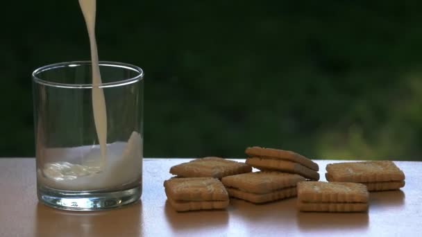 Leche Fresca Vertida Vaso Junto Unas Galletas Sobre Una Mesa — Vídeos de Stock